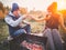 Happy couple smiling and roast marshmallows on campfire on nature. Cheerful man and woman rest at the fire fight with skewers with