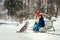 Happy couple is spending their time with siberian dog in the snowy park during the snowfall. The charming red head girl