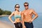 Happy couple in sports clothes and shades on beach