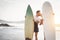 Happy couple of surfer kissing before to go to surf - Sporty people having a tender moment on the beach at sunset