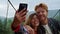 Happy couple taking photo on mobile phone. Friends enjoy traveling in mountains.