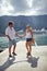 Happy couple on vacation. Lovers holding hand walking on pier. Cruiser, mountains, sea in background. Travel, togetherness,