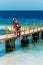 Happy couple on vacation strolling along a wooden pier above the tropical turquoise ocean.