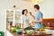 Happy couple, vegetarians preparing healthy meal, sandwhich, salad in the kitchen together. Guy feeding his girlfriend