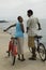 Happy Couple Walking With Bicycles On Beach