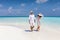 Happy couple walks down a tropical beach