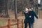 happy couple in warm knitted hat and scarf walking outdoor in autumn forest