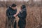 Happy couple in warm knitted hat and scarf walking outdoor in autumn forest