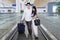 Happy couple wearing white on an airport moving walkway