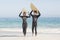 Happy couple in wetsuit carrying surfboard over the head