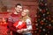 Happy Couple in winter pullovers smiling and holding big red gift box