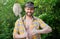 Happy cowboy giving thumbs up holding garden spade. Unshaven man smiling in cowboy hat