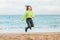 Happy crazy cool girl jumping on the beach - blue sea background