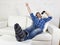 Happy crazy man on couch listening to music holding mobile phone as microphone