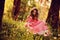 Happy curly child girl in pink princess dress on the walk in summer forest