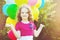 Happy curly girl with colorful balloon in summer park. Toning to