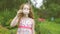 Happy curly haired girl blowing soap bubbles in summer park.