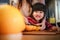 Happy Cute 3-4 Years Old Girl with her Mom Slice some Orange on Wooden Table in Pantry Room. Young Girl is Learning Cook with her