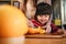 Happy Cute 3-4 Years Old Girl with her Mom Slice some Orange on Wooden Table in Pantry Room. Young Girl is Learning Cook with her