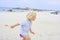 Happy cute active little boy playing in the sand at a beach in Brittany