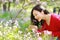 Happy cute Asian Chinese nature beautiful woman smell flower and listen to music in a spring park enjoy free time
