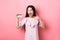 Happy cute asian woman showing plastic credit card, recommending bank special deal, standing against pink background