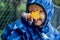 Happy cute caucasian little boy toddler preschooler wearing blue raincoat jacket holding yellow maple leaf on a rainy autumn day.