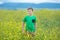 Happy cute handsome little kid boy on green grass lawn with blooming yellow dandelion flowers on sunny spring or summer day. Littl