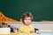 Happy cute industrious child is sitting at a desk indoors. Individual tutoring.