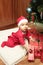 Happy cute little baby in Santa& x27;s costume near Xmas tree decorating
