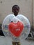 A happy cute little boy holding a heart shape balloon