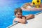 Happy cute little boy teenager in swimming pool. Active games on water, vacation, holidays concept. Chocolate donut.