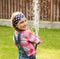 Happy cute little girl pouring water from a hose