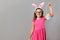 Happy cute little girl wearing easter bunny ears and glasses on gray background. The child is holding a basket of eggs