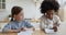 Happy cute little multiracial friends girls doing homework indoors.