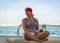 Happy cute sunburnt girl in a red bandana is sitting on a yacht on background of the blue sky and blue sea