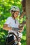 Happy, cute, young boy in white t shirt and helmet having fun and playing at adventure park, holding ropes