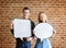 Happy cute young couple holding an empty placard thought bubble