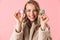 Happy cute young pretty woman posing isolated over pink wall background holding cake macaroons sweeties