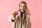 Happy cute young pretty woman posing isolated over pink wall background holding cake macaroons sweeties