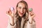 Happy cute young pretty woman posing isolated over pink wall background holding cake macaroons sweeties