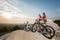 Happy cyclist couple in the sunglasses sitting on a rock