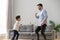 Happy dad and kid son dancing together in living room