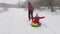 Happy dad is lucky on a sled along the snow-white road of a child. Christmas holidays and travel. A fun game for adults