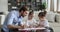 Happy dad playing with adorable daughters drawing at home table