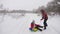 Happy dad sledges a child on a snowy road. Christmas Holidays. father plays with his daughter in a winter park. The