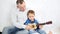 Happy dad teaches son to play guitar