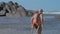 Happy daddy walks with boy on back along empty ocean beach