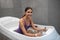 Happy dark-haired female in purple swimming suit receiving hydrotherapy