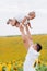 Happy daughter with daddy in the sunflower field. happy family having fun in the field of sunflowers. Dad throws his daughter in a